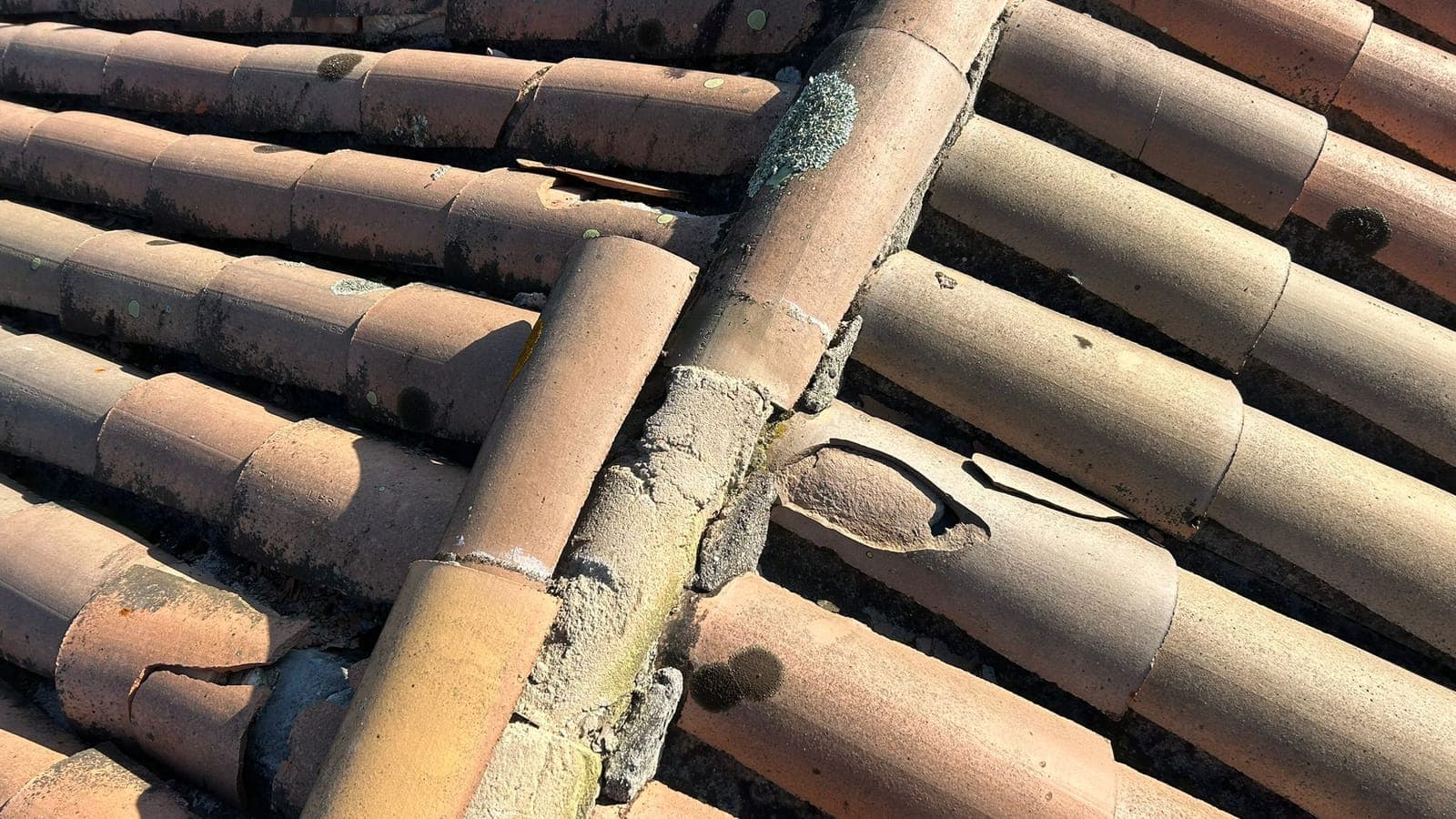 Arêtier en tuiles canal anciennes, tuile fendue et mortier fissuré