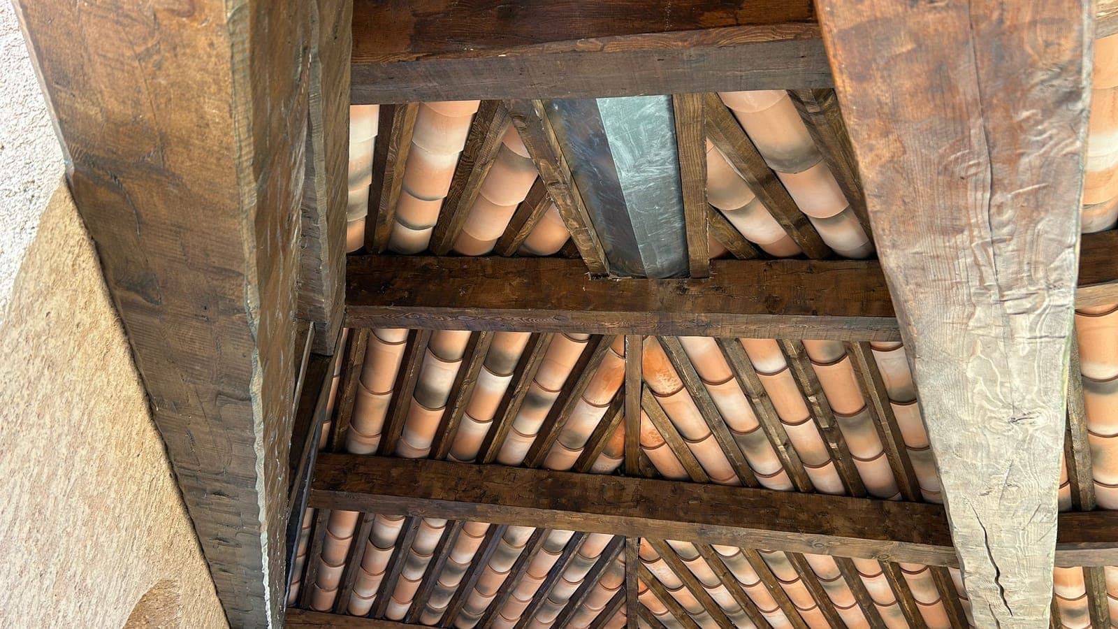 Charpente en bois apparente, chevrons et tuiles canal vus du dessous